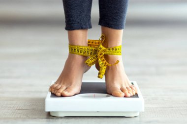 Tanınmayan Hintli kadın terazinin üzerinde ayaklarıyla duruyor, ağırlığını kontrol ediyor. Bin yıllık hanımefendiye yakından bakınca zayıflatma ve yeme bozukluğundan muzdarip olma fikrine kafayı takmış.