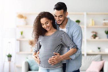 Sevgili Orta Doğulu genç adam kocası güzel hamile karısına sarılıyor. Koca göbekli, bin yıllık Arap ailesi bebek bekliyor. İç mekan, fotokopi odası. Aile, doğum, hamilelik kavramı