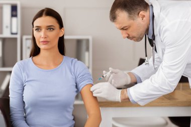Covid-19 Aşılama. Coronavirus 'a karşı aşı olan kadın hasta hastanede doktor randevusu sırasında kas içi aşıya maruz kalıyor. Corona Virüs Bağışıklığı