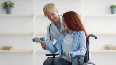 Tekerlekli sandalyedeki kızıl saçlı genç bir kız aktif olarak evde destekleyici biriyle egzersiz yapıyor. Atmosfer teşvik edici ve uygunluğa odaklı..
