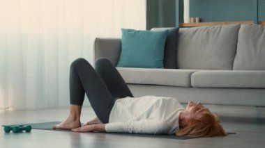 Son sınıf öğrencisi bir kadın evdeki yoga minderinde egzersiz yapıyor, spor rutinine odaklanıyor. Doğal ışık ve rahat bir atmosfer içeriyor, sağlıklı bir yaşam tarzını destekliyor..