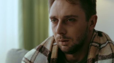 Bin yıllık bir adam oturma odasında yalnız oturuyor, hasta ve yorgun görünüyor. Yalnız ve depresif görünüyor, battaniyeyle örtülmüş, soğuk algınlığıyla ya da loş bir alanda griple savaşıyor..