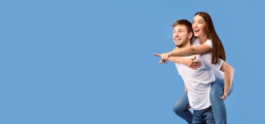 Mor stüdyo duvarından izole edilmiş fotokopi alanını işaret eden sürpriz çift, kızı sırtında taşıyor.