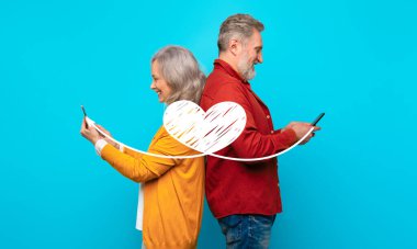 A couple stands back to back, holding smartphones while sending affectionate messages. They celebrate St. Valentines Day with a joyful and connected atmosphere. clipart