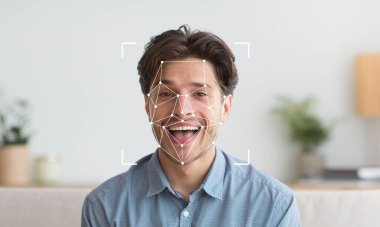 Yüz tanıma teknolojisi uygulanırken bir adam neşeli bir yüz ifadesi sergiler. Aydınlatıcı ve hoş bir ortam, onun tanımlanabilir özelliklerine ve duygularına odaklanmasını sağlıyor..