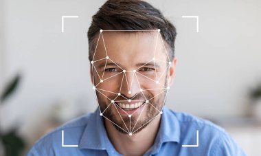 Yüz tanıma sistemi yüz hatlarını belirlerken bir adam gülümsüyor. Mekan parlak ve modern, teknoloji gösterisi için mükemmel bir zemin sağlıyor..