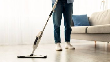 Kadının, ahşap kaplama döşemeleri, su spreyi ve doldurulabilir şişeyi temizleme maddesiyle yıkadığı yakın çekim kesimi. Ev işleri konsepti. Bulanık Arkaplan, Boş Kopyalama Boşluğu