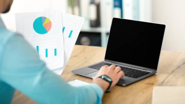 Tanımlanamayan Arap işadamı dizüstü bilgisayarda çalışıyor şirket ofisinde boş ekranla, web sitesi tasarımı için modelleme yapıyor. Belgeleri ve taşınabilir bilgisayarı olan adam yöneticisi, reklam için alan