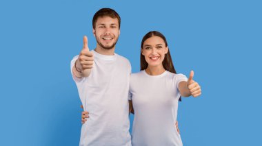 Tavsiye ediyoruz. Heyecanlı erkek ve kız başparmak hareketi yapıyorlar, Pastel mor stüdyo duvarına sarılıyorlar, afiş