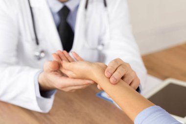 Tıbbi ve Sağlık Konsepti. Erkek doktorun hastaların elini tutarken, nabzını ölçerken, kan basıncını ölçerken. Kardiyoloji ve hipertansiyon. Kadını muayene eden doktor.