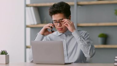 Uzaktan kumandalı bir ortamda işine odaklanmış bir adam dizüstü bilgisayarında yazarken bir telefon görüşmesi yapıyor. Arkaplandaki raflarda kitaplar ve bitkiler var, verimli bir ortam yaratıyorlar..