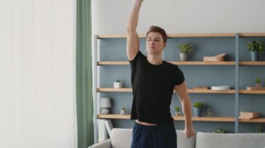 Sportif bir genç adam evde spor yapıyor, atletizmini ve sağlıklı bir yaşam tarzına olan bağlılığını gösteriyor. Enerjik atmosfer canlı ve motive edici bir titreşim yayar..