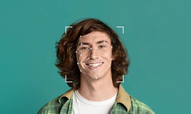 Kıvırcık saçlı genç bir şahıs kameraya gülümserken yüz tanıma programı anahtar özellikleri ön plana çıkarıyor. Bu basit ve temiz bir ortamda gelişmiş tanımlama teknolojisini gösteriyor..