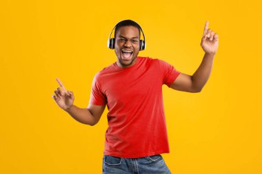 Neşeli siyahi adam şarkı söylüyor ve dans ediyor. İnternette müzik dinliyor, kulaklık takıyor ve sarı stüdyoda eğleniyor. Millennial Man Harika Parça Listesi 'nin tadını çıkarıyor. Müzik Uygulaması Konsepti