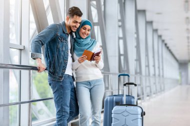 Havalimanında dikilen mutlu İslami Yolcu Çifti portresi, Terminalde uçuş bekleyen genç Arap erkek ve Müslüman Kadın, bilet ve pasaport kontrolü, kopyalama alanı