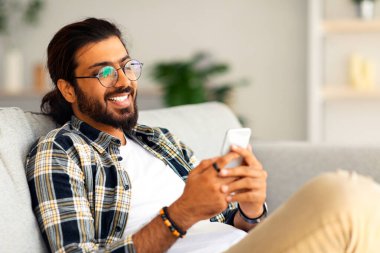 Yakışıklı Hintli genç adam evdeki kanepede rahatlıyor, akıllı telefondan oyun oynuyor, fotokopi çekiyor. Neşeli Arap adam cep telefonunda flört uygulaması kullanıyor, bayanlarla sohbet ediyor.