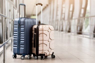 Seyahat modası. Boş havaalanı koridorunda duran iki plastik bavulun yakın çekimi, Terminal Salonunda bekleyen şık bavullar, Hava Taşıma ve Tatil Rezervasyonları