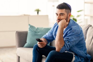 Sıkıcı Televizyon Programı. Sıkıcı Yahudi Adam TV izliyor uzaktan kumandayla kanal değiştiriyor evdeki koltukta oturuyor. Hoşnutsuz İzleyici İlginç Olmayan Film İzliyor, Yalnız Hissediyor