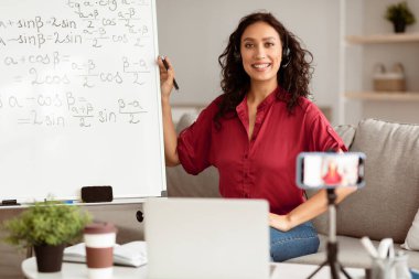 Çevrimiçi Öğrenme Konsepti. Kulaklık takmış gülümseyen bayan öğretmenin portresi. Öğrencilere matematik formüllerini anlatıyor. Heyecanlı kadın poz veriyor ve kameraya bakıyor, video sınıfını kaydediyor.