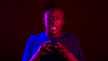 Yakışıklı bir milenyum adamı elinde bir kumandayı tutarken oyuna yoğun bir şekilde odaklanır. Parlak neon ışıkları onun etrafında fütüristik bir atmosfer yaratarak oyun deneyimini arttırıyor..