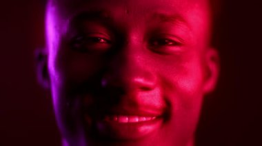 Havalı, bin yıllık Afro-Amerikan bir adam canlı neon arka planına güvenle gülümsüyor. Kurulum, modern estetiğin gelecekçilik ve modaya uygun hipster titreşimlerini birleştirdiğini vurguluyor..