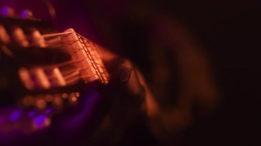 Afrika kökenli Amerikalı bir adam sahnede canlı, neon ışıklı bir arka plana karşı gitar yeteneklerini sergiliyor. Atmosfer enerjik ve modern. Havalı tarzını vurguluyor..