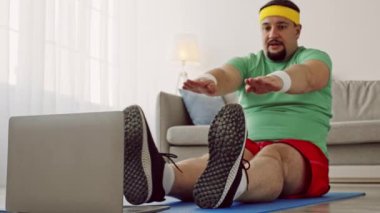 Bir milenyum adamı evdeki yoga minderinde esneme egzersizleri yapar, rehberlik için dizüstü bilgisayar kullanır. Kilo vermeyi hedefleyen spor yolculuğuna kendini adamış gibi görünüyor..