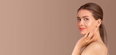 Bir kadın cilt bakımı rutinine girer ve yüzüne şımartıcı ürünler uygular. Etrafı boş, tarafsız bir geçmişle çevriliyken sakinlik ve güven yayıyor..