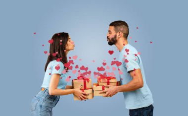 Orta Doğulu çift birbirlerine yaslanmış kırmızı kurdelelere sarılı hediye kutularını tutarken romantik bir öpücük paylaşıyorlar. Kalpler onları sarar, aşkın ve kutlamanın özünü yakalar..