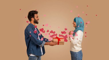 Hintli çift Sevgililer Günü 'nü kutlarken sevgi dolu bir anı paylaşıyor. Erkek, kadının sevgisini sembolize eden yüzen kalplerle çevrili güzel bir hediye sunar..