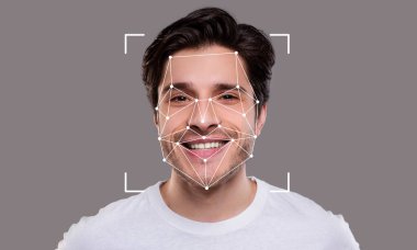 Genç bir adam yüz tanıma teknolojisi tarafından incelenirken gülümsüyor. Geometrik kaplama, gelişmiş tanımlama becerilerini gösteren anahtar yüz özelliklerini vurgular.