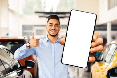 Beyaz ekranlı akıllı telefonu gösteren yakışıklı Arap adam, otomobil galerisinde yeni araba seçerken mobil uygulaması kullanıyor, online okuma önerileri, modelleme