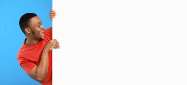 İndirim teklifi. Boş beyaz panoya bakan heyecanlı siyah adam mavi arka planda boş yeri olan büyük posterin yanında poz veriyor. Reklam afişi ve mesajının reklamını yapan adam. Mockup, Panorama