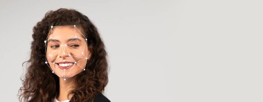 Kıvırcık saçlı bir kadın, yüz tanıma teknolojisi yüz hatlarını incelerken gülümsüyor. Arkaplan boş, ifadesini ve kullanılan teknolojiyi vurguluyor..