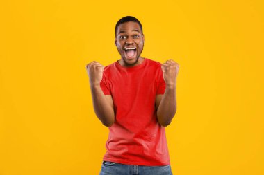Zaferin sevinci. Heyecanlı Afrikalı Amerikalı adam, sarı stüdyonun arka planına bakıp 