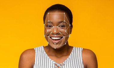 Yüz tanıma teknolojisi yüz hatlarını belirlerken kısa saçlı bir kadın gülümsüyor. Parlak sarı arka plan onun neşeli yüz ifadesine ve teknolojiye odaklanmasını sağlar..