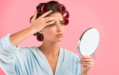 First Wrinkles. Unhappy Housewife Touching Face Frowning Looking In Round Mirror Standing On Yellow Background. Studio Shot
