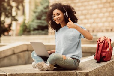 Afro-Amerikalı Öğrenci Laptop Kullanıyor Başparmak Öğren Çevrimiçi Açık havada Kolej Kampüsü 'nün yanında oturuyor. E-öğrenme ve uzaktan eğitim kavramını seviyorum.