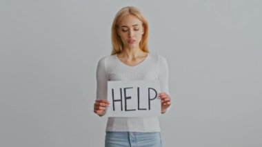 Genç bir kadın minimalist bir ortamda yalnız duruyor, düşünceli ve içe dönük görünüyor. Düşünceli ifadesi, aile içi sorunlarla ilgili kişisel mücadelelere işaret ediyor..