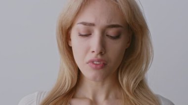 Uzun, açık renk saçlı bir kadın hüzünlü bir yüz ifadesi sergiler, ciddi aile içi şiddet sorununu düşünürken gözleri kapalıdır. Tarafsız bir ortamda yaşadığı duygusal karmaşaya odaklanmış durumda..