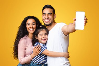 Beyaz ekranlı, boş akıllı telefon gösterisi yapan, Orta Doğulu anneyi seven baba ve küçük kızı yeni mobil uygulamayı kucaklayan ve eğlenen üç kişilik neşeli bir Arap ailesi.