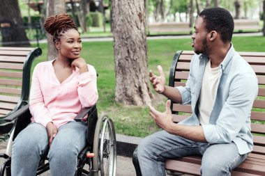 Genç Afro-Amerikalı bir adam bankta oturuyor, dışarıda fiziksel engelli bayan arkadaşıyla konuşuyor. Milenyum siyahi kadın tekerlekli sandalyede erkek arkadaşıyla parkta sohbet ediyor.