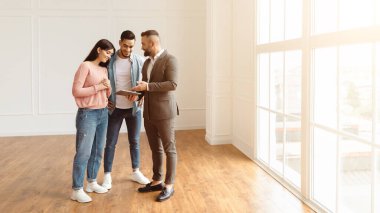 Profesyonel Emlakçı Takım Elbiseli Dijital Tableti İnşaat Projesiyle Gösteriyor, Ev Planını Tartışıyor, Mutlu Aileye Daire Satıyor. Çift Satın Alma Dairesi, Boş Oda, Sancak, Panorama