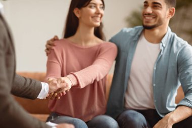 Başarılı Evlilik Terapisi Konsepti. Mutlu Milenyum Çifti Aile Danışmanıyla tokalaşıyor Evliliği kurtardığı ve yardım ettiği için şükran duyuyor, gülümseyen karı ve koca kanepeye oturuyor, seçici odaklanıyor.