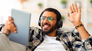 Mutlu sakallı orta doğulu adam gözlük takıyor. Evdeki koltukta dinlenirken kulaklık takıyor. Neşeli Hintli adam arkadaşlarıyla ya da sevgilileriyle görüntülü sohbet ediyor.