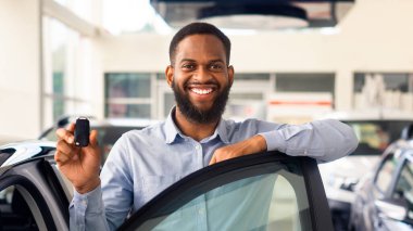 Mutlu Sahip. Neşeli Siyah Adam Lüks Araç ve Tutucu Anahtarlar 'ın yanında duruyor, Modern Otomobil Aldıktan sonra Afro-Amerikan Erkek Poz Verme Merkezi