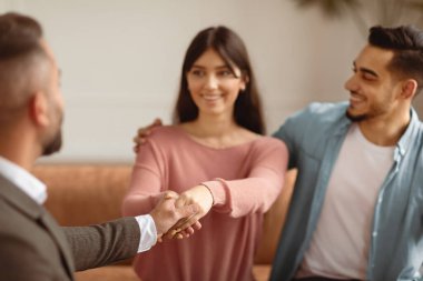Başarılı bir evlilik terapisi. Mutlu bir milenyum Arap çifti aile danışmanıyla el sıkışıyor evliliklerini kurtardığı için teşekkür ediyor, gülümseyen karı ve koca kanepeye oturuyor, seçici odaklanıyor.