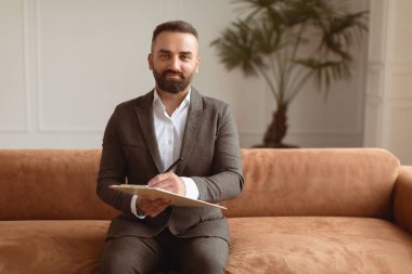 Profesyonel Psikoterapi Konsepti. Başarılı Psikolog 'un portresi, Takım Elbise Giyen, Kalem Giyen, Ofisindeki koltukta oturan, panoya yazan kameraya gülümseyen,