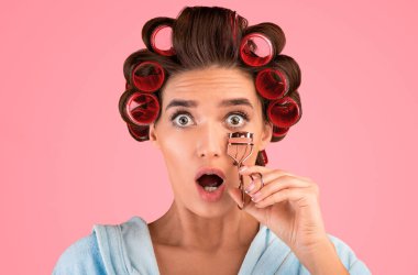 Ev hanımı Kirpikli Şok Edici Kıvırcık, Stüdyoda Sarı Arkaplanda Duran Kamera Pozisyonuna Bakıyor. Güzellik ve Makyaj.