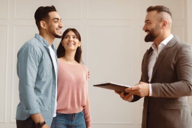 Uzmanlarla istişare. Toplantıda müşterilerle konuşan profesyonel mali danışman ya da satıcı, sigorta ipoteği komisyoncusu genç çifte danışıyor, gülümseyen aileye iş teklifi yapıyor.